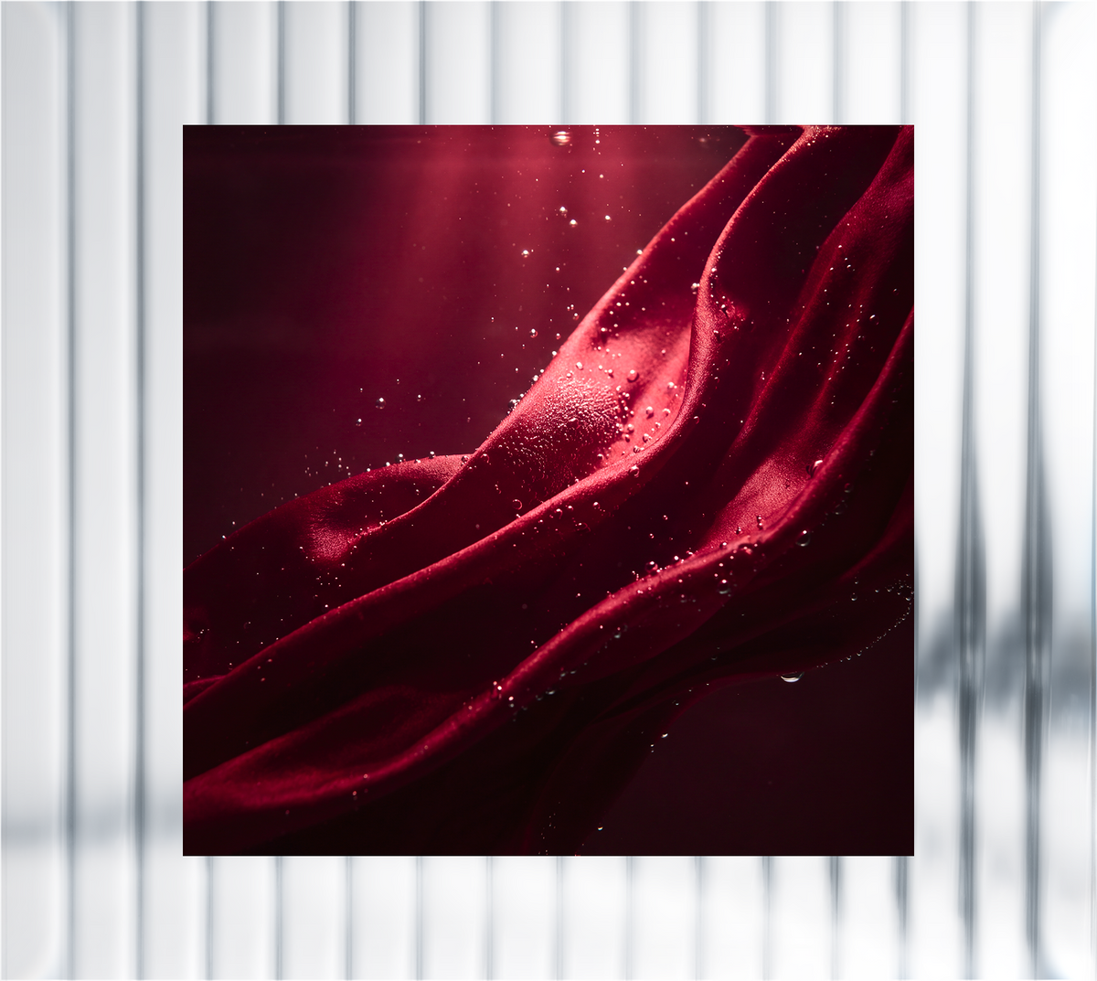 Abstract close-up of deep red flowing fabric with sparkling droplets, representing skin aging and cellular changes