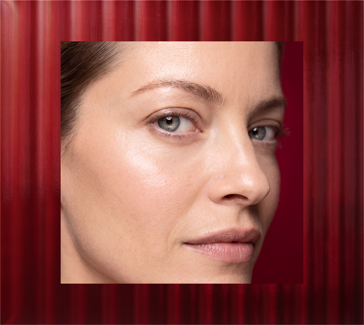 Close-up portrait of a woman with smooth facial skin against a deep red textured background