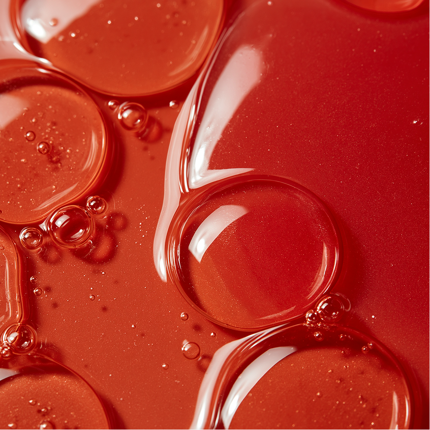 Close-up of glossy red serum bubbles representing postbiotic ferments