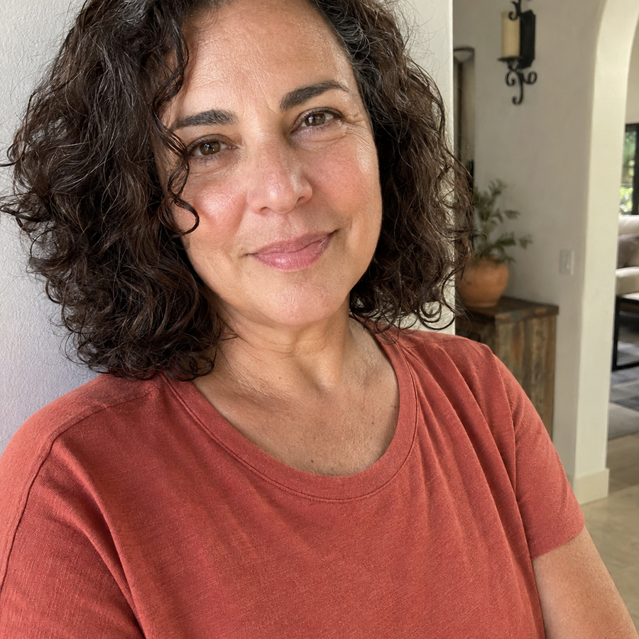 Woman with curly dark hair smiling in a red shirt
