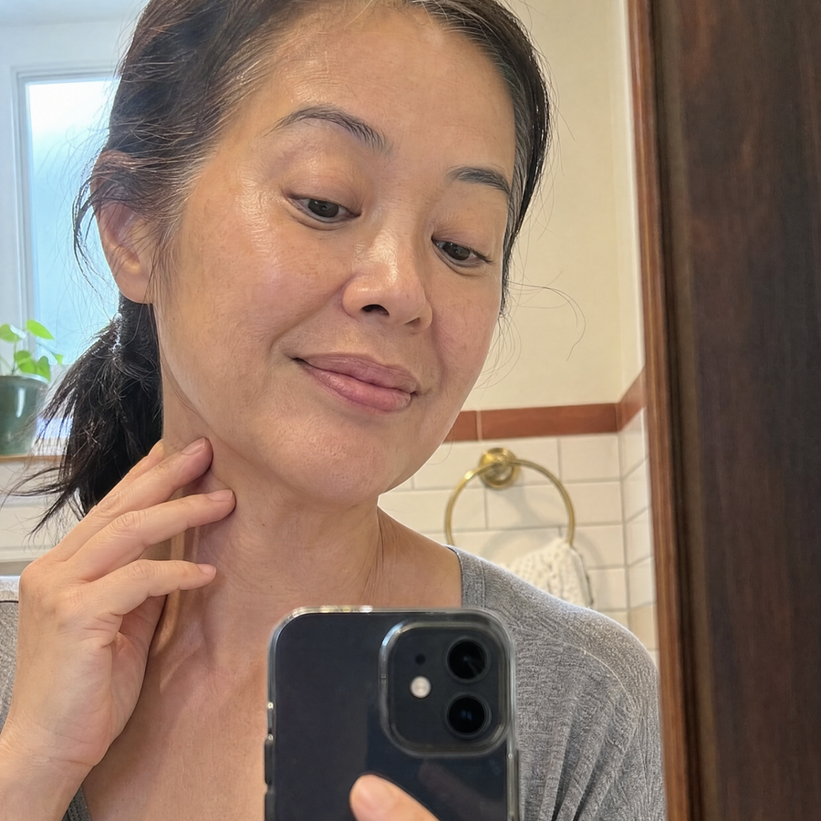 Woman taking a mirror selfie while gently touching her neck